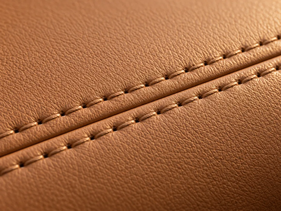 Illustrative close-up of tan leather grain and parallel stitched seams