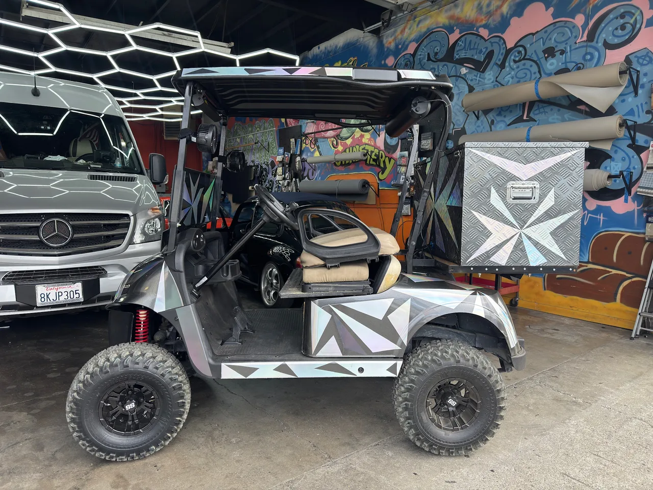 Golf cart during the upholstery work, with partly disassembled beige seating and an uncovered steering wheel in the San Jose workshop.