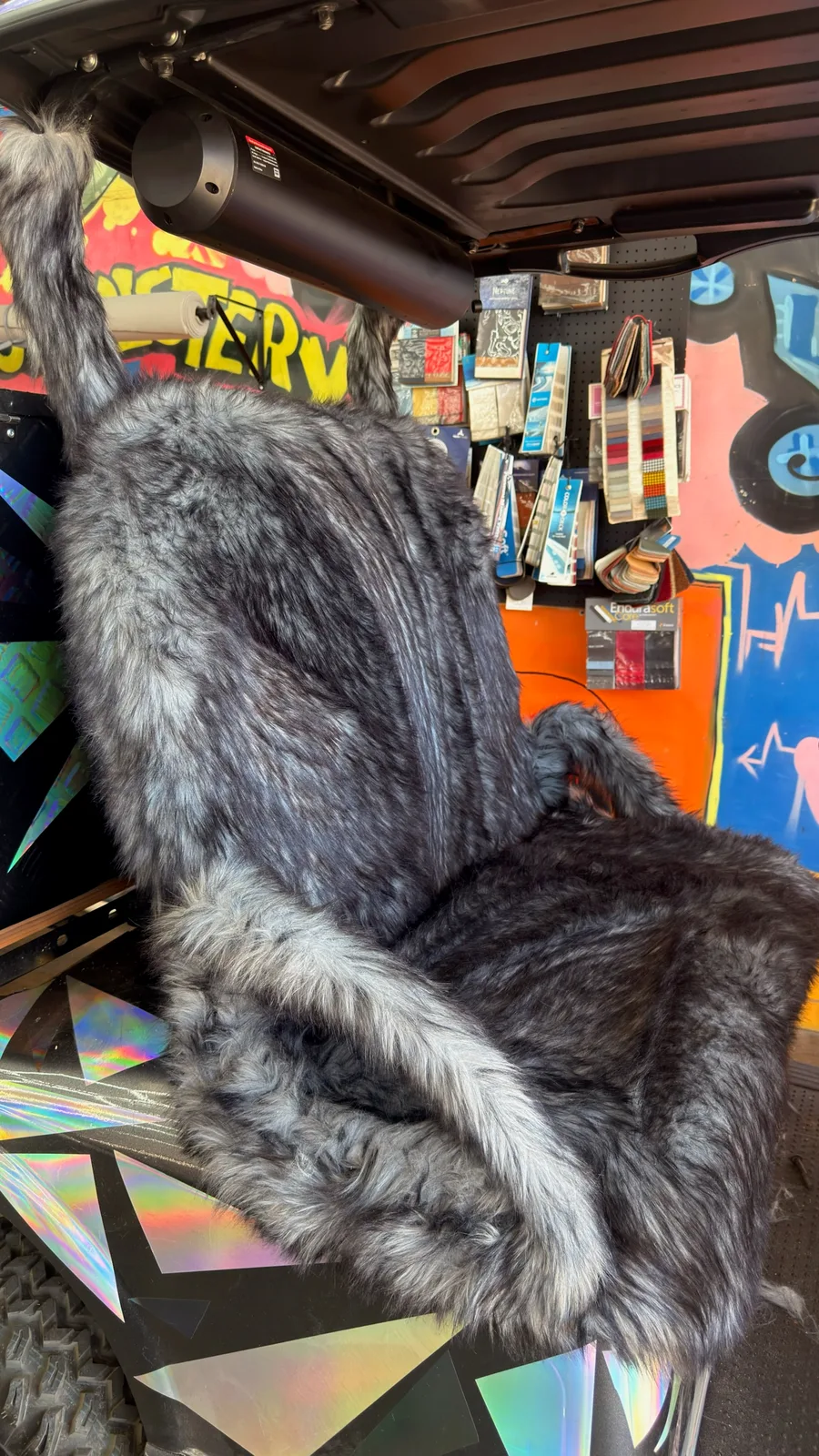 Close view of the gray fur-textured seat, tall upholstered backrest and matching armrest.