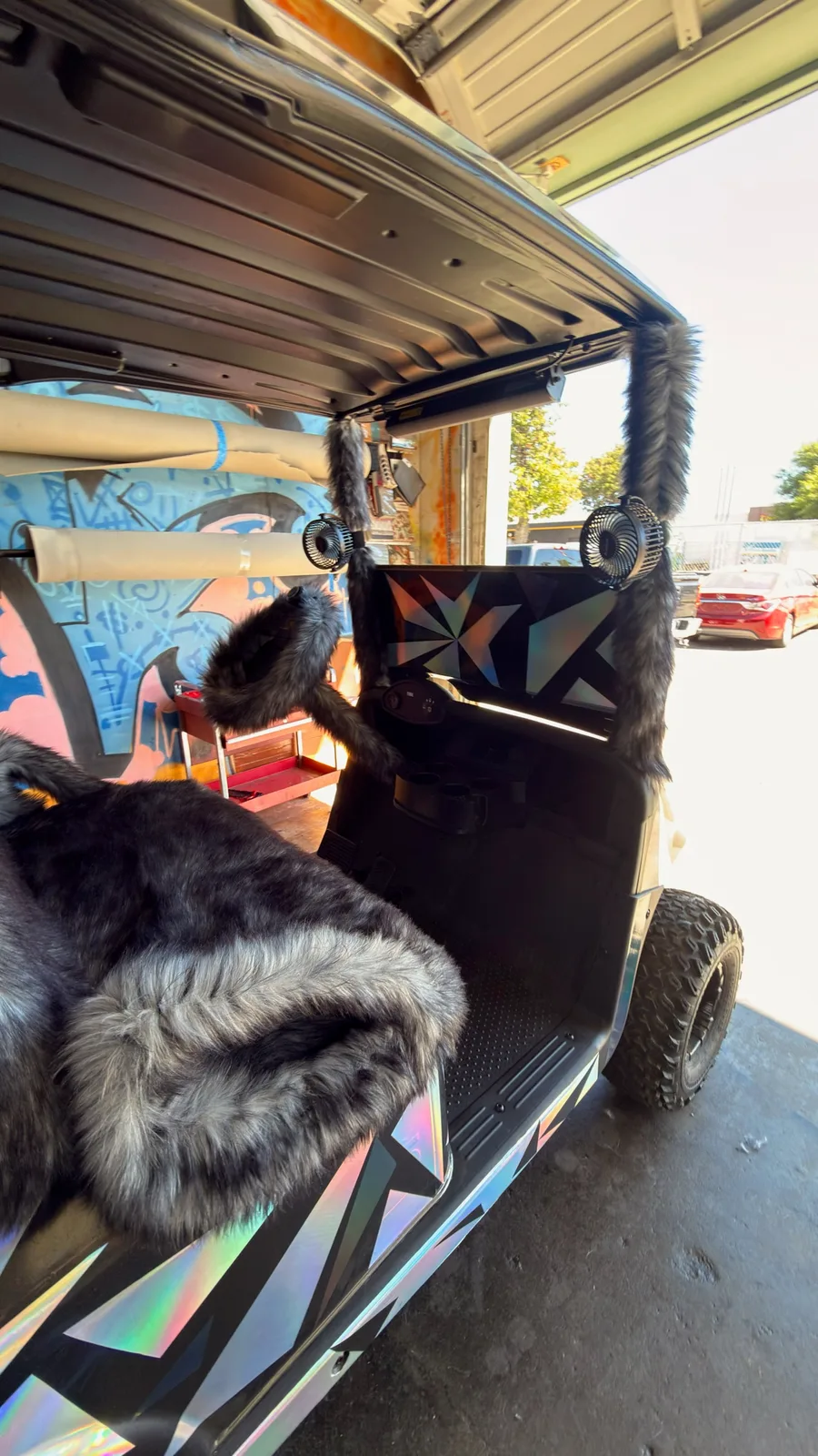 The golf cart's steering wheel and column covered in matching gray, fur-textured upholstery.